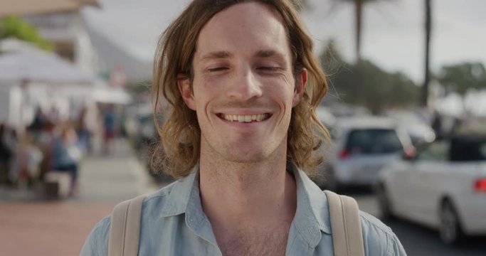 portrait of happy young caucasian man smiling enjoying independent vacation lifestyle handsome male tourist on sunny urban beachfront street slow motion