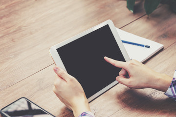 Hand woman using tablet computer on wooden table with Vintage toned.