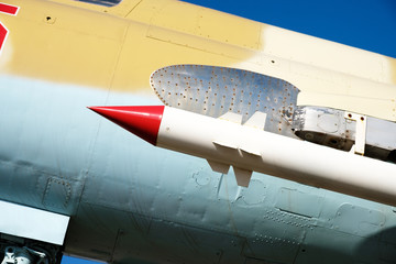 A military missile is located on the wing of a fighter plane, military armament