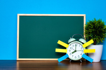 Note paper sticky and vintage alarm clock and blank green chalkboard on table with copy space for add text notice something, list memo and schedule concept.
