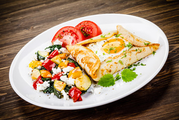 Crepes with eggs on wooden background