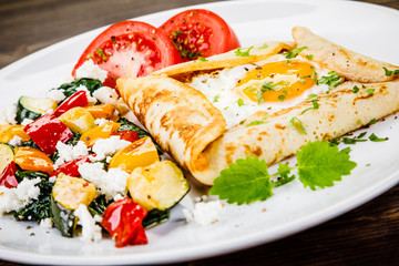 Crepes with eggs on wooden background