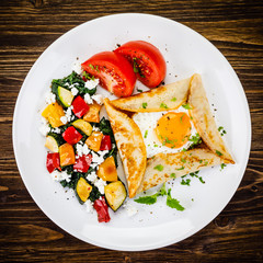 Crepes with eggs on wooden background