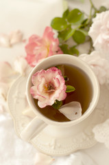 Aromatic tea in a vintage mug and pink roses, a delicious and beautiful breakfast. Pastel shades,