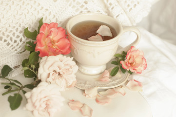 Obraz na płótnie Canvas Aromatic tea in a vintage mug and pink roses, a delicious and beautiful breakfast. Pastel shades,