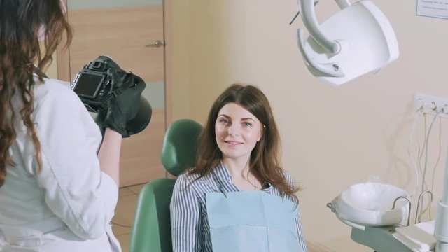 A dark-haired dentist takes pictures of her patient on a professional camera after dental treatment to make a collage before-after. Slow motion
