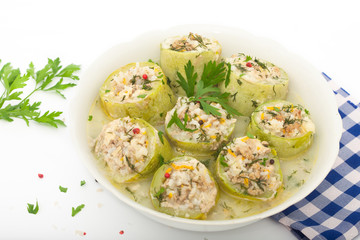 Stuffed zucchini with rice, minced meat and vegetables in white bowl. Decorated with dill, parsley and red pepper.