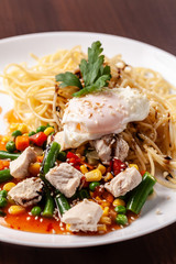 Italian pasta Spaghetti with vegetables and chicken. With red salsa sauce and basil. It is on the table in the restaurant. Copy space, selective focus