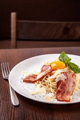 Italian pasta spaghetti carbonara, with fried bacon, parmesan cheese and egg yolk. It is on the table in the restaurant. Copy space, selective focus