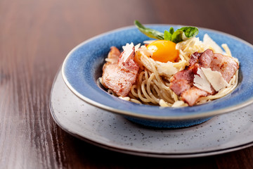 Italian pasta spaghetti carbonara, with fried bacon, parmesan cheese and egg yolk. It is on the table in the restaurant. Copy space, selective focus