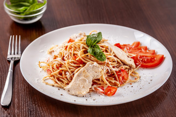 Italian pasta spaghetti with red tomato sauce, tomatoes and grilled chicken. It is on the table in the restaurant. Copy space, selective focus