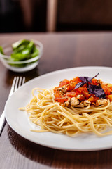 Italian pasta spaghetti with red tomato sauce, tomatoes and grilled chicken. It is on the table in the restaurant. Copy space, selective focus