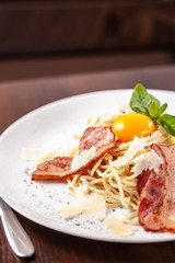 Italian pasta spaghetti carbonara, with fried bacon, parmesan cheese and egg yolk. It is on the table in the restaurant. Copy space, selective focus
