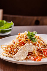 Italian pasta spaghetti with red tomato sauce, tomatoes and grilled chicken. It is on the table in the restaurant. Copy space, selective focus