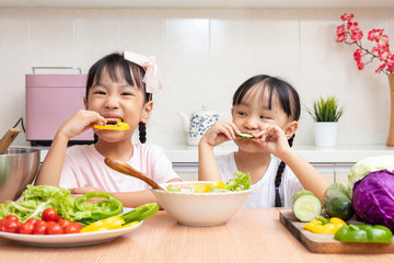 Asian Chinese little sisters eating salad in the kitchen