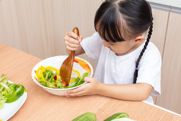 Asian Chinese little girl making salad in the kitchen