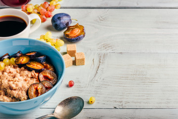 Porridge with fresh plum, green grapes and cup of coffee.