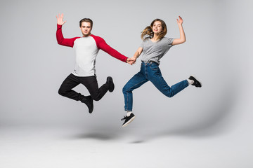 Fototapeta na wymiar He vs She. Full length portrait of attractive, playful, cheerful, comic couple in casual outfit, jeans, shirts jumping over grey background