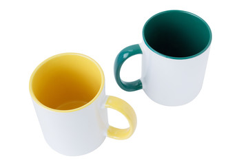 Two white mugs, with a green and yellow handle on a white background.  Isolated.  View from above.