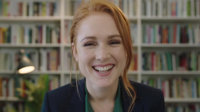 portrait of beautiful young red head business woman intern laughing cheerful enjoying professional career opportunity in library background