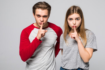 Amazed European female and male make silence sign, keep fore fingers on lips, tell secret and...