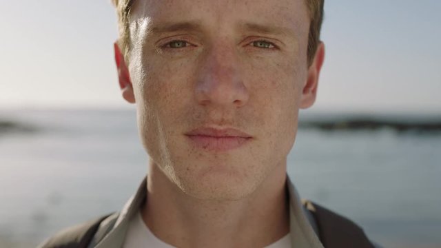 close up portrait of handsome young man looking thoughtful pensive on seaside background