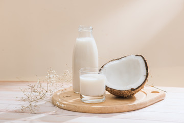 Coconut milk in bottle and glass on table with copy space