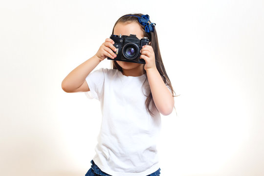 Girl taking a picture with a professional retro camera isolated on white