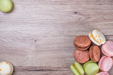 Delicious multicolored french macaroons or macaron on a wooden background whith place for insert text. Copy space