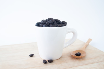 Fototapeta na wymiar Coffee beans in white cup on wooden table, Coffee lover concept