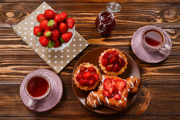 Tea drinking with tartlets and cakes with strawberries