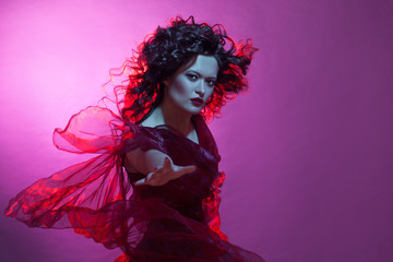 Dancing woman with flying red dress. Beautiful Gothic girl like a witch
