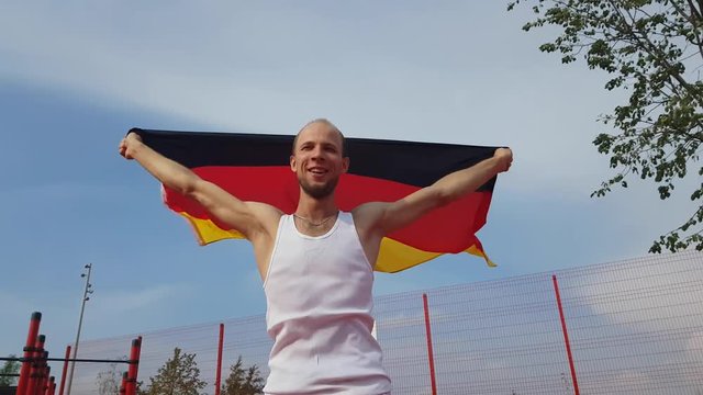 Young Man Holding German National Flag To The Sky With Two Hands