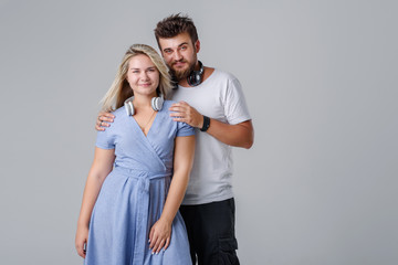 Fototapeta premium Young cheerful and cheerful couple with wireless headphones, smiling against a gray background. Club DJs