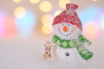 Kleiner Schneemann mit Lichtern im Hintergrund
