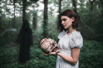 Victim holds human skull, death on background