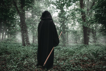 Death with a scythe in the dark misty forest