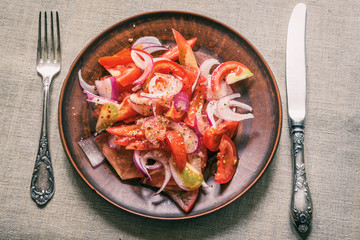 Delicious simple salad of tomato and red onion on a rustic pottery plate