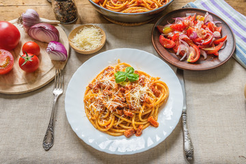 Pasta Amatratciana with Parmesan cheese and a basil elaf on a white plate
