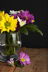 Beautiful fall autumn bouquet arrangement of chrysanthemum flowers in glass on black background and wooden table.