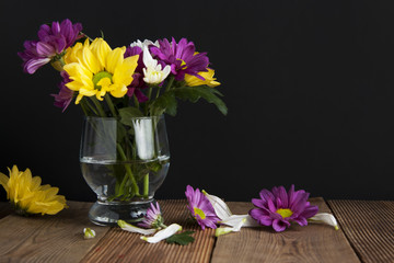 Beautiful fall autumn bouquet arrangement of chrysanthemum flowers in glass on black background and wooden table with copy space.