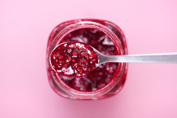 Jar full of fruit jam with a silver spoon on top viewed from above. Shallow depth of field. Top view