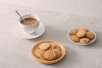 Cup of coffee with milk or cappuccino with cookies on light stone background. Drink with caffeine or cocoa with milk. Coffee break concept.