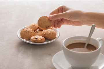 Hand picking cookie from plate. Drink with caffeine or cocoa with milk.