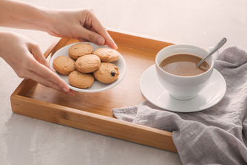 Hand putting cookies on plate into tray. Breakfast concept with coffee