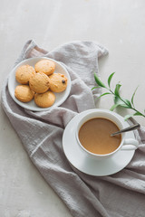 Closeup of coffee with milk in white cup and tasty cookies. Shot on light stone background
