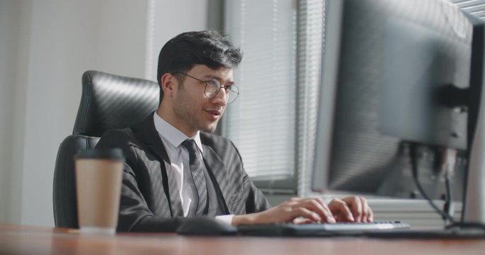 young south asian businessman working at computer,then doing victory dance after promotion. busineessman happy after successful deal. business, victory concept 4k