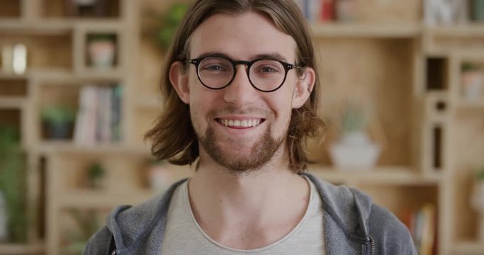 close up portrait of cute young man smiling happy student enjoying success geek wearing glasses looking at camera real people series