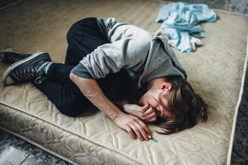 Male drug addict sleeping in bed after dose