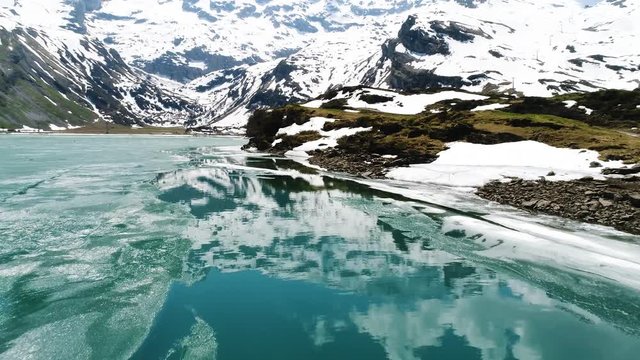 aerial, mountain reflection in clear blue mountain lake. melting ice in engelberg switzerland
